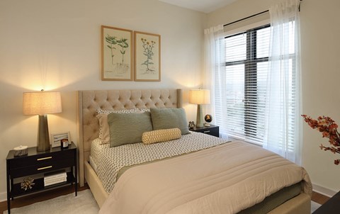 A bedroom with a large bed and two lamps.