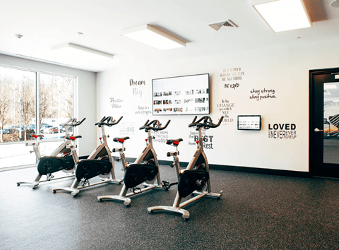 A gym with exercise bikes and inspirational quotes on the wall.
