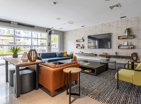 A living room with a blue couch and a television on the wall.