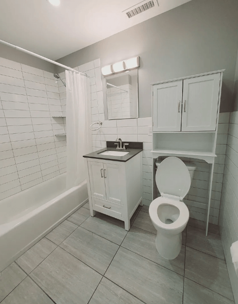 A white toilet in a bathroom with a white cabinet and a white shower curtain.