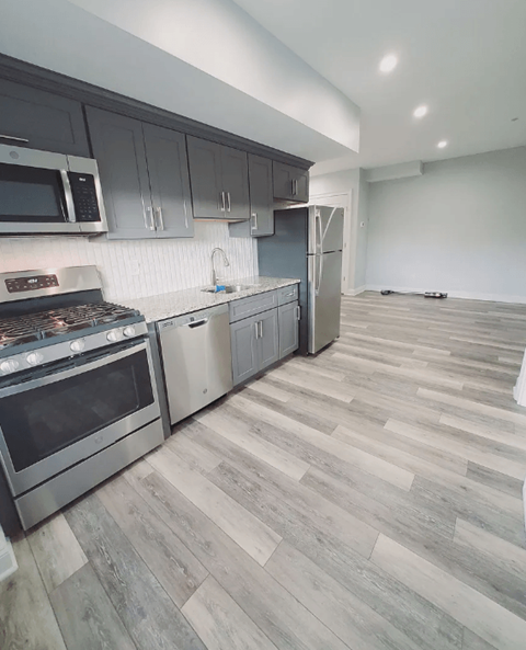 A kitchen with a refrigerator, oven, and microwave.