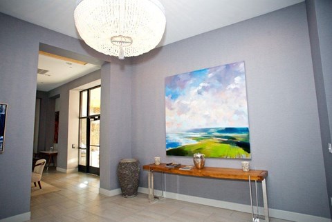 A large painting of a landscape hangs on the wall above a wooden table.