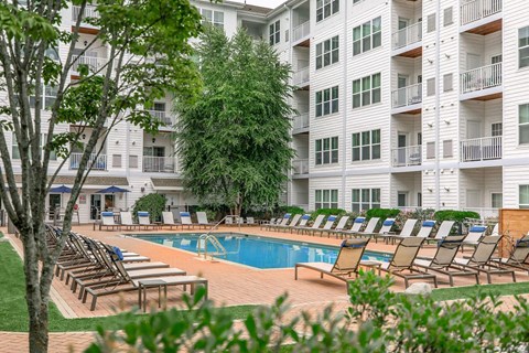 A pool area with sun loungers and a white building in the background.