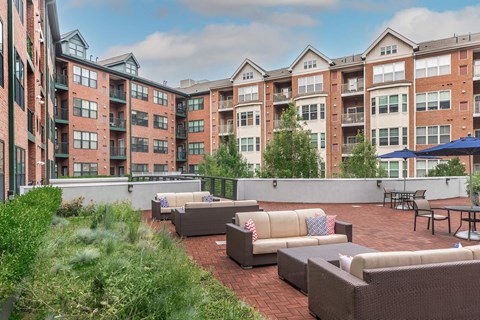 A patio area with couches and tables in front of apartment buildings.
