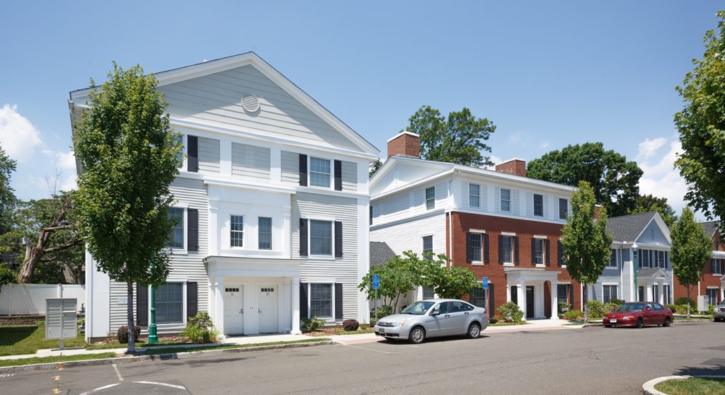 A white two story house with a red car parked in front.