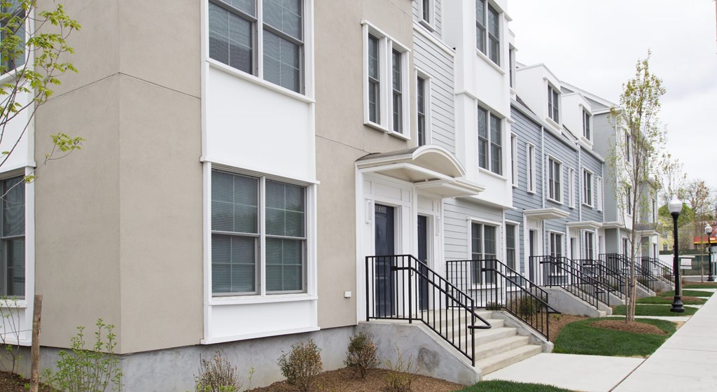 A row of townhouses with white and grey exteriors and black railings.