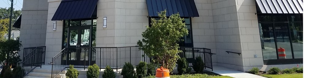 A tree in a pot is in front of a building.