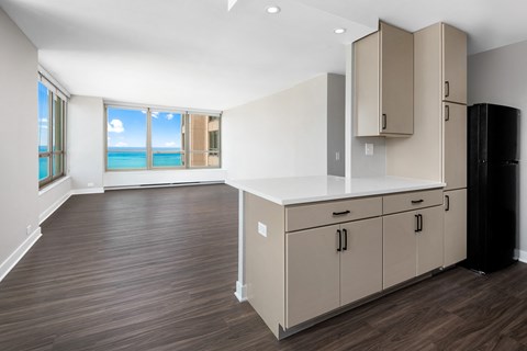 A kitchen with a black refrigerator and wooden floors.