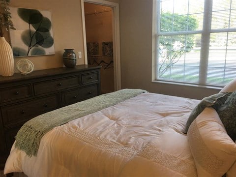 a bedroom with a bed and a dresser and a window