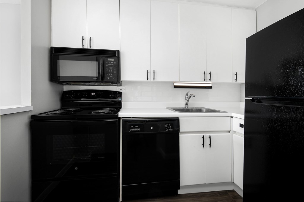 A black and white photo of a kitchen with white cabinets.
