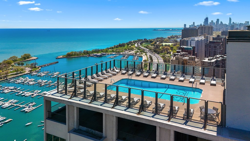 A marina with boats and a pool with chairs.