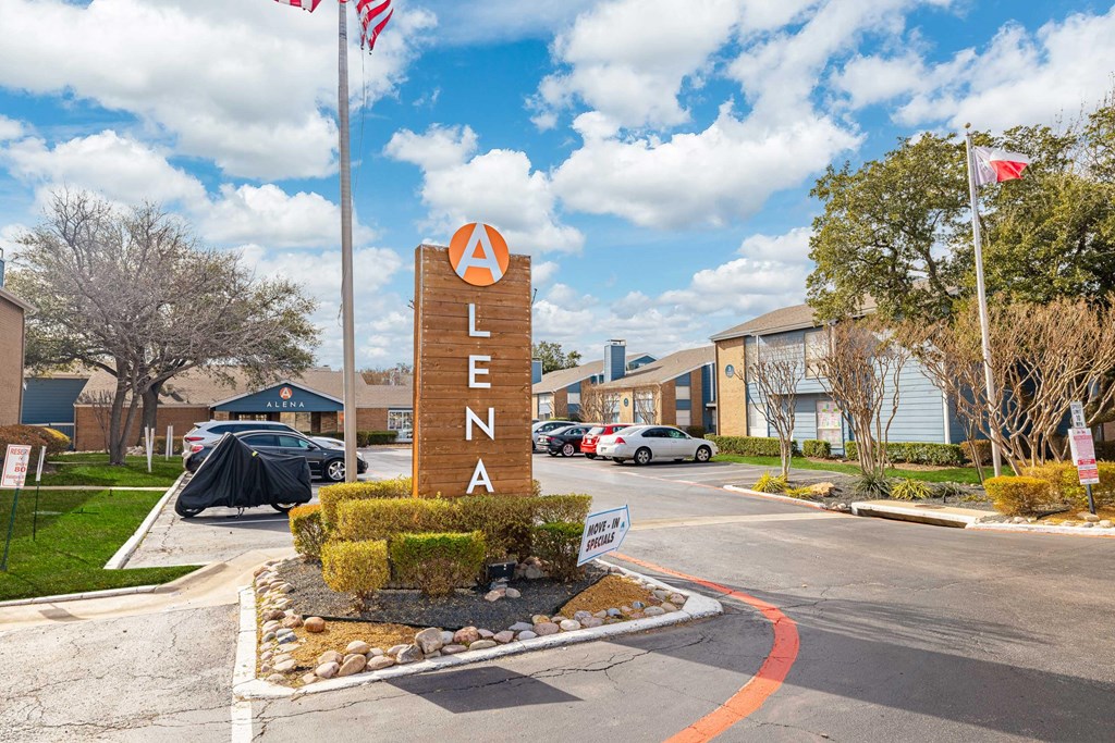 ALENA sign in front of a building with cars parked in the background.