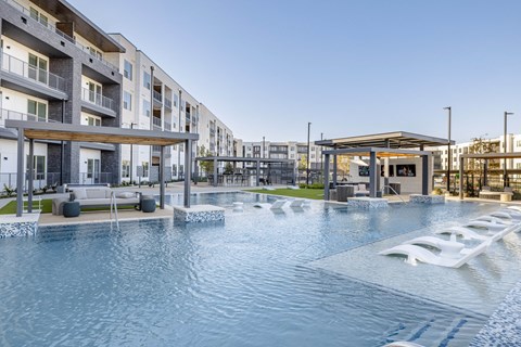 A modern pool area with a water slide and apartment buildings in the background.