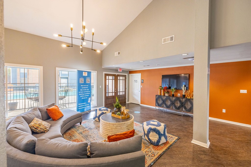 A living room with a grey couch and a round table with a vase on it.