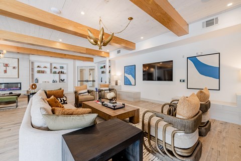 A modern living room with a white sofa, a wooden coffee table, and a large abstract painting on the wall.