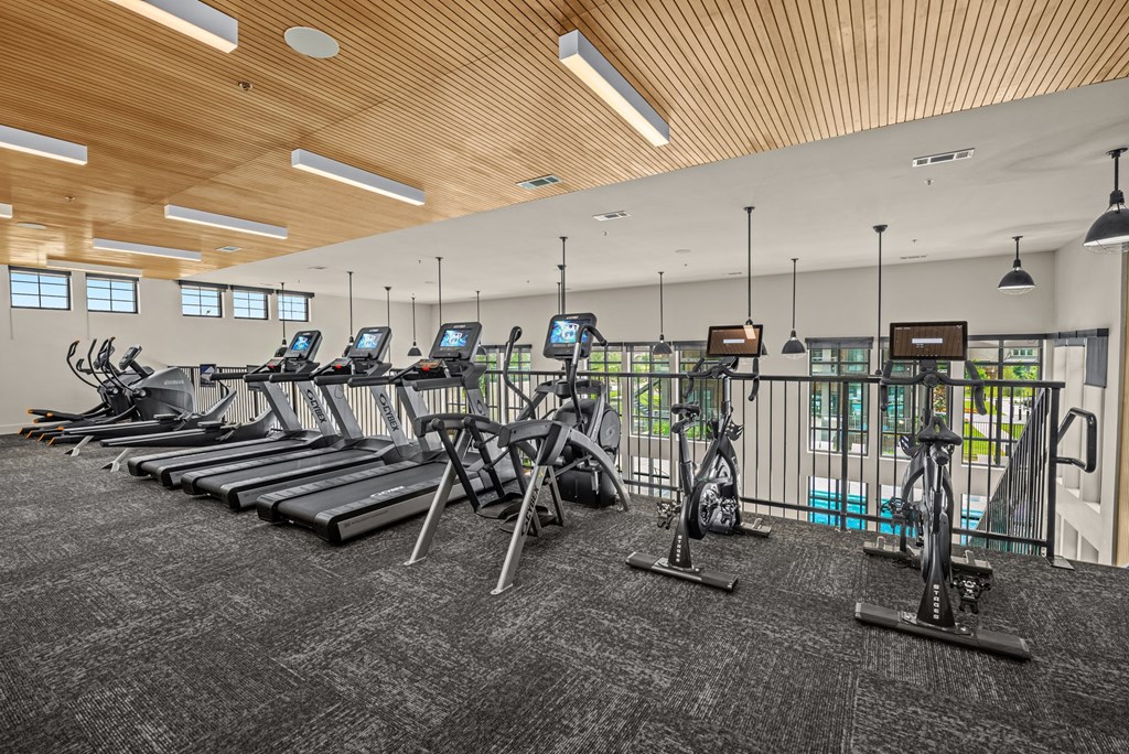a spacious fitness center with cardio machines and treadmills