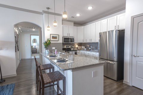 A kitchen with a table set for two with a view of the refrigerator and oven.