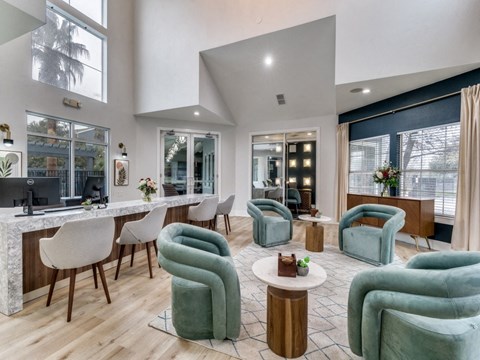 a living room with green chairs and a bar and windows