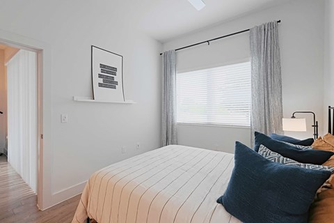 A bedroom with a bed, pillows, and a picture on the wall.