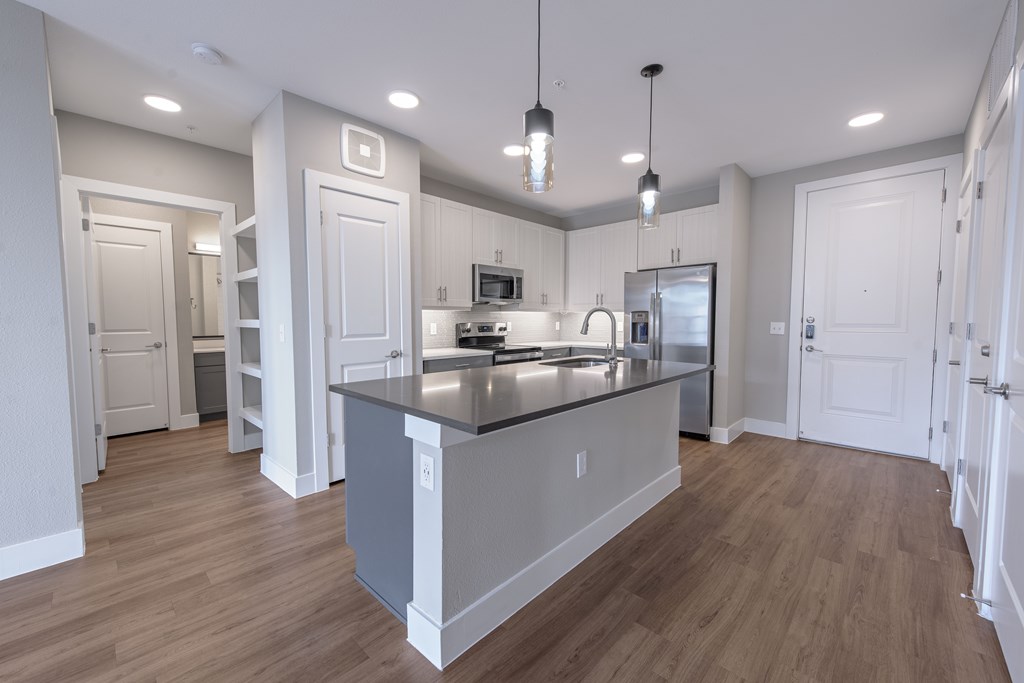 A modern kitchen with a large island and pendant lights.