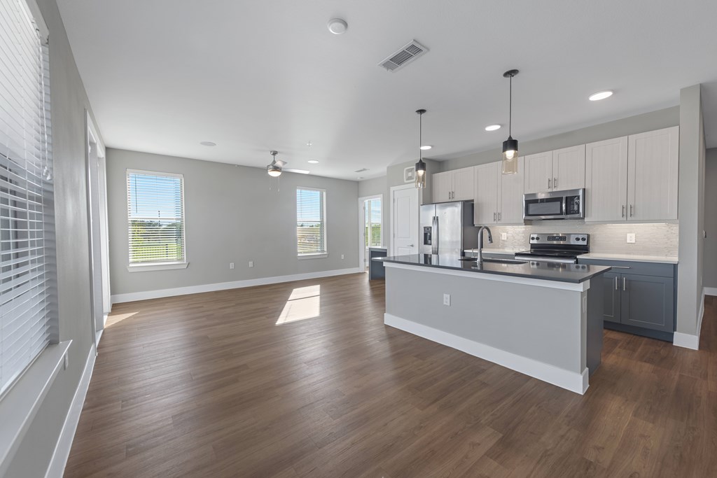 A spacious kitchen with wooden floors and modern appliances.