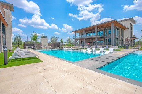 a swimming pool with lounge chairs and a building in the background