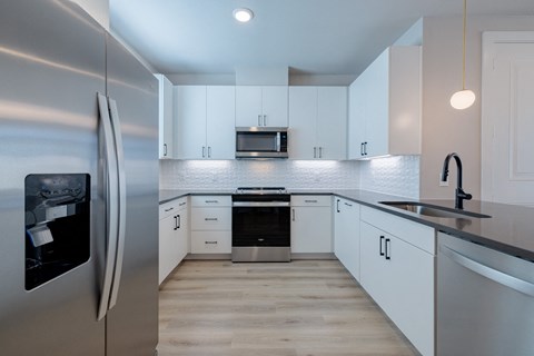 A modern kitchen with a stainless steel refrigerator and white cabinets.