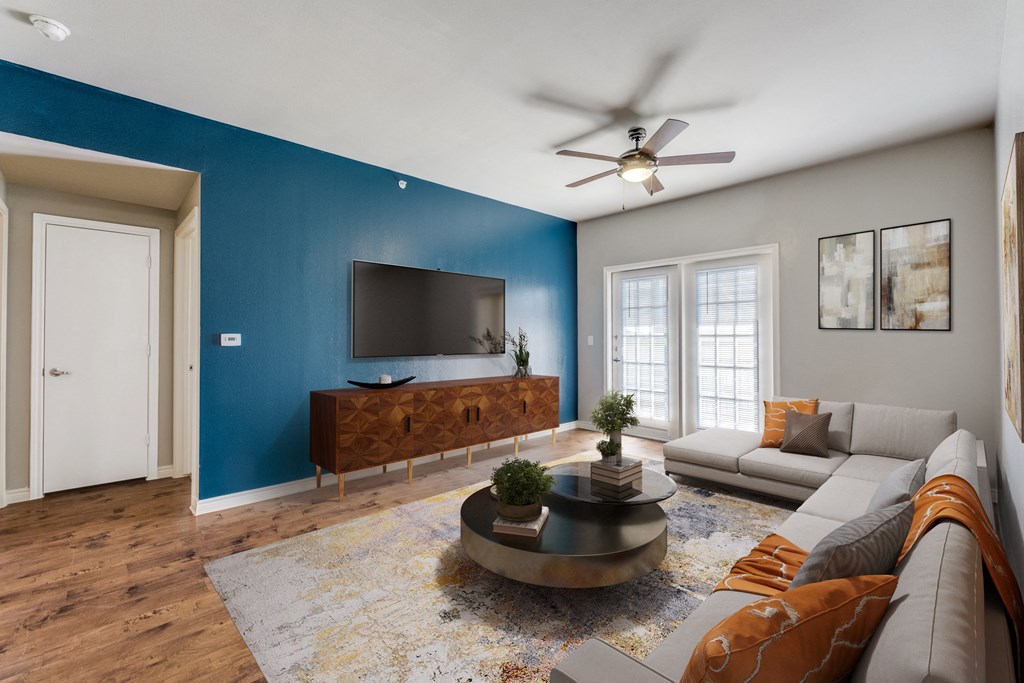 a living room with a blue accent wall and a couch and a tv  at Valor at Harlingen, Harlingen, TX