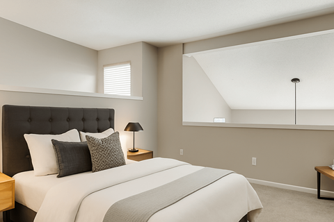 A bedroom with a large bed and a nightstand with a lamp.