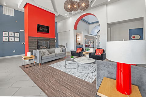 a living room with gray couches and a red accent wall  at Collective on Riverside, Austin, TX, 78741