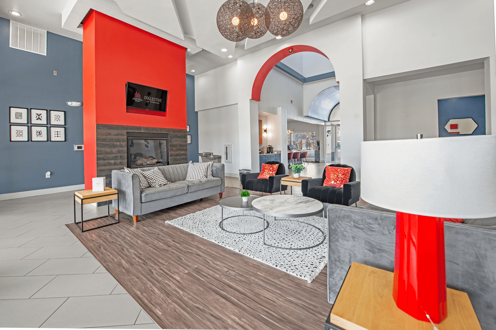A living room with a grey couch and a red accent wall.