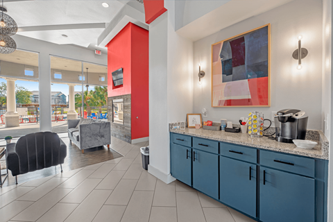 A kitchen area with blue cabinets and a red accent wall.