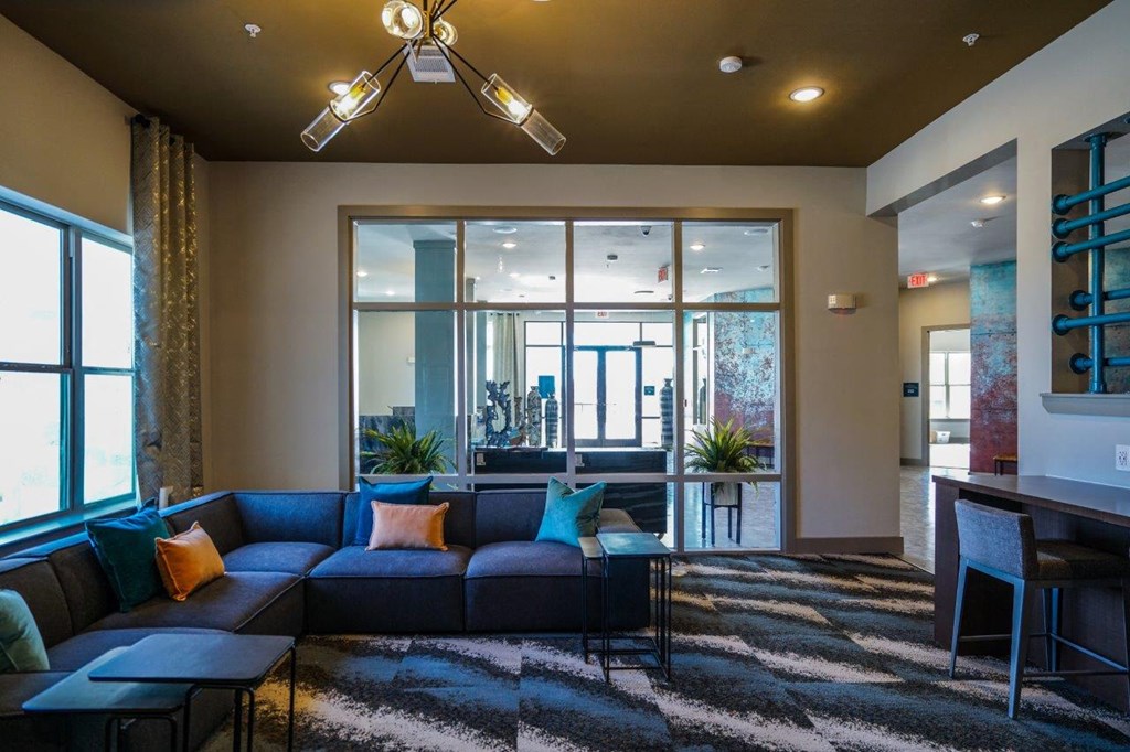 A living room with a blue couch and a black and white rug at The Grand at Manor Apartments, Manor