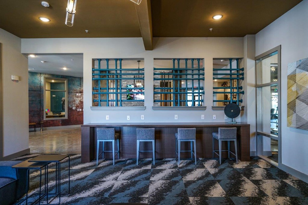 A room with a bar and a black and white checkered rug at The Grand at Manor Apartments, Manor, 78653