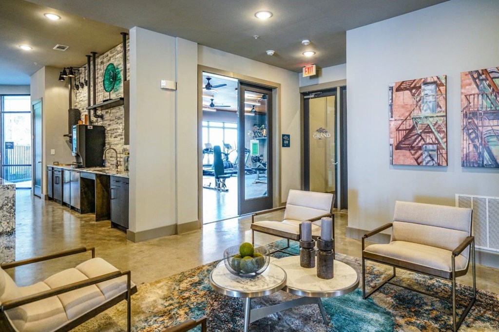 A living room with a sofa, armchair, and coffee table at The Grand at Manor Apartments, Texas 78653