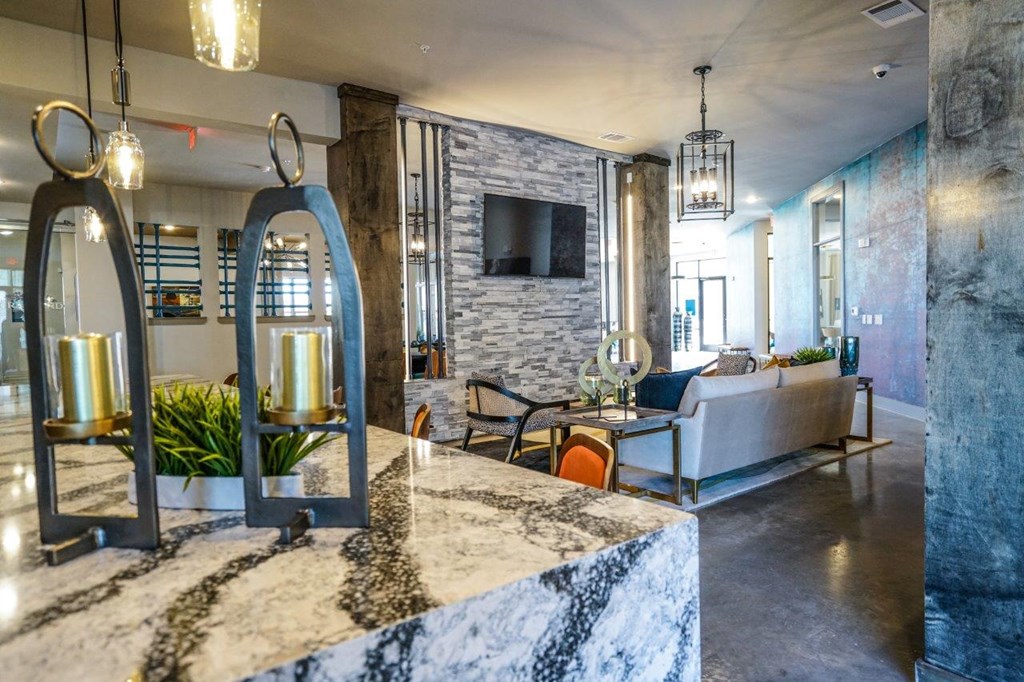 A modern living room with a stone fireplace and a grey sofa at The Grand at Manor Apartments, Manor, TX, 78653