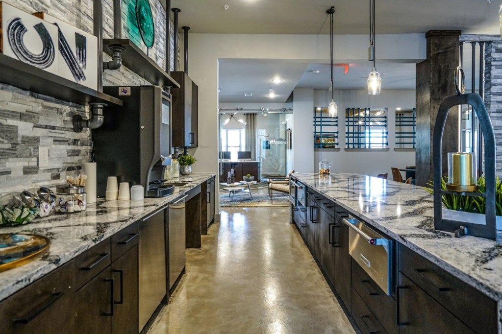 A modern kitchen with dark wood cabinets and a marble countertop at The Grand at Manor Apartments, Manor, Texas