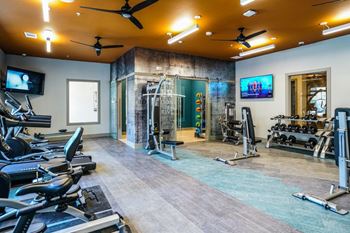 A gym with treadmills, exercise bikes, and a television.