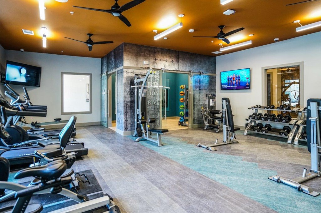 A gym with treadmills, exercise bikes, and a television at The Grand at Manor Apartments, Manor