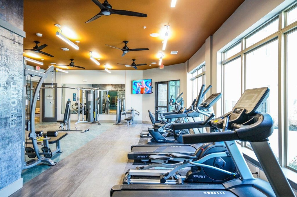 A gym with treadmills, exercise bikes, and a television at The Grand at Manor Apartments, Manor, Texas