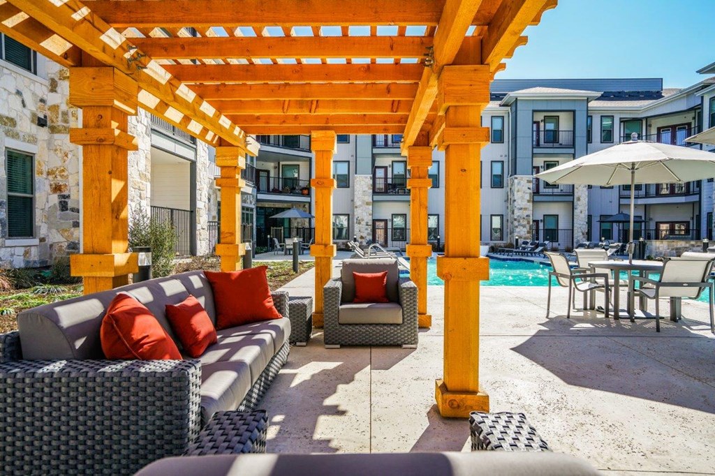 A patio with a yellow pergola and a pool table at The Grand at Manor Apartments, Manor, 78653