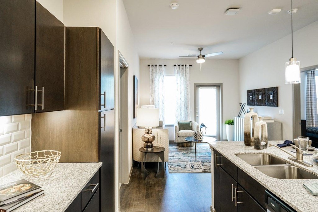 A modern kitchen with dark wood cabinets and a white countertop at The Grand at Manor Apartments, Texas 78653