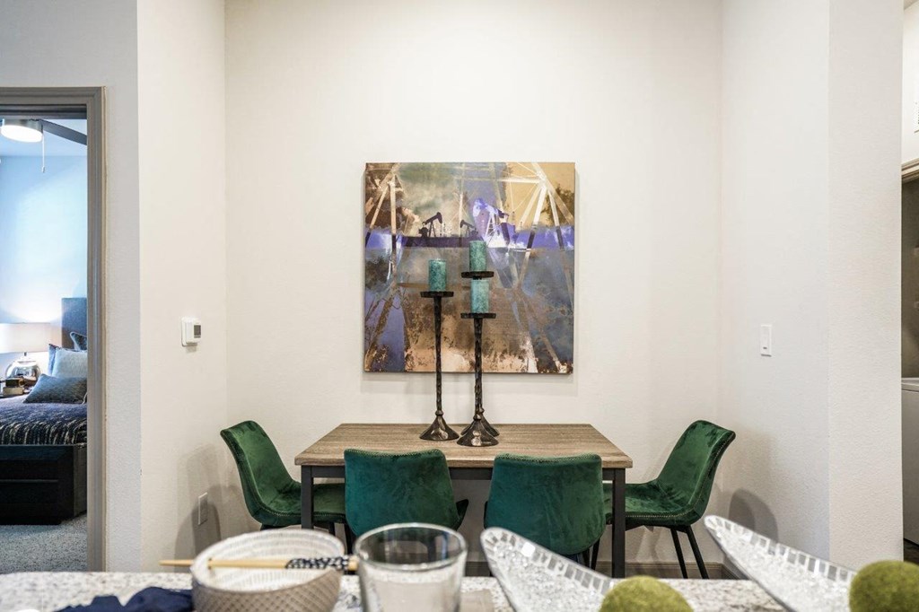A painting hangs on the wall above a table with chairs around it at The Grand at Manor Apartments, Texas