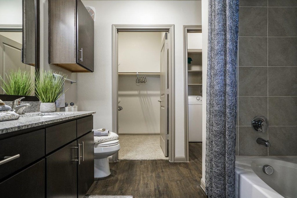 A bathroom with a toilet, sink, and bathtub at The Grand at Manor Apartments, Manor, TX