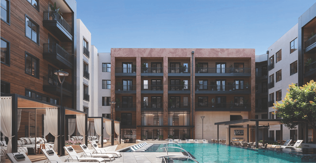 A pool surrounded by lounge chairs and umbrellas in front of a building.