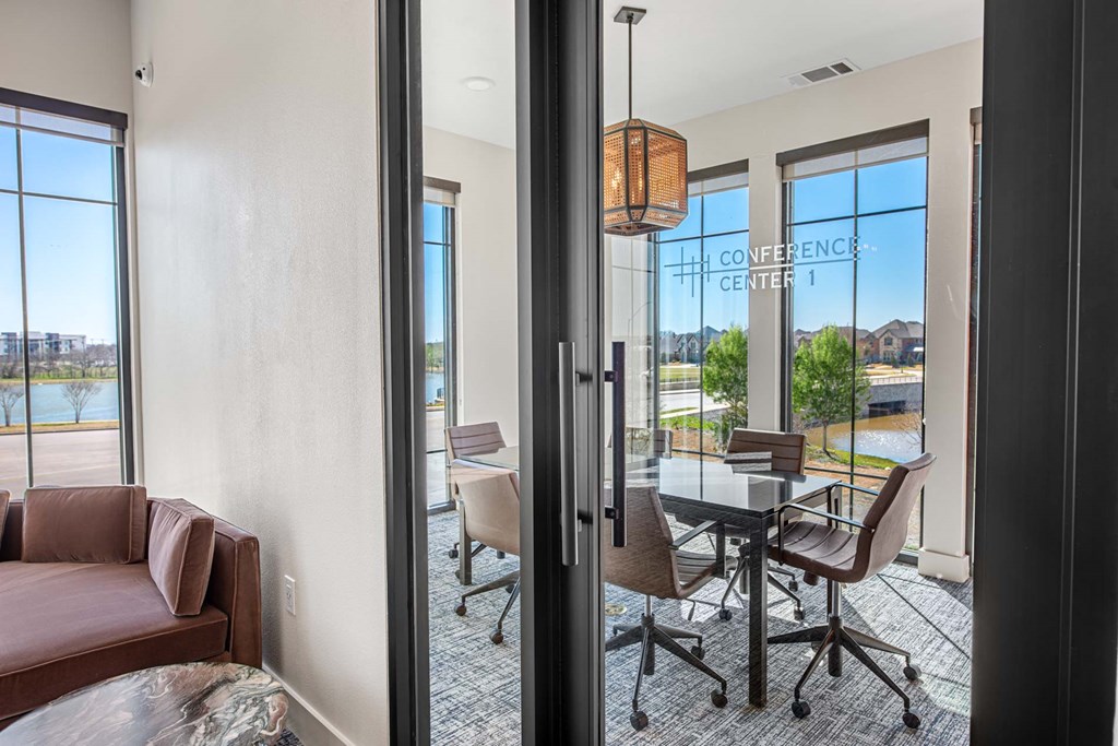 a dining area with a glass table and chairs and large windows