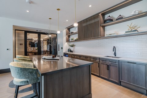 A modern kitchen with a dark wood island and green chairs.