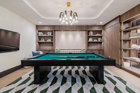 A pool table in a room with a green and white rug.