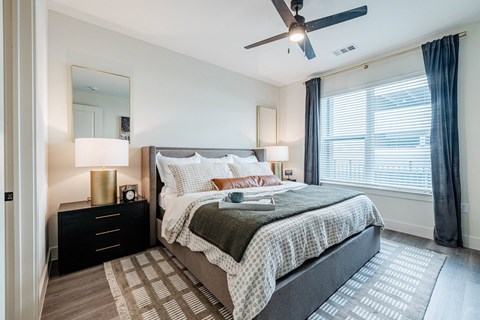 A bedroom with a bed, nightstand, and window.