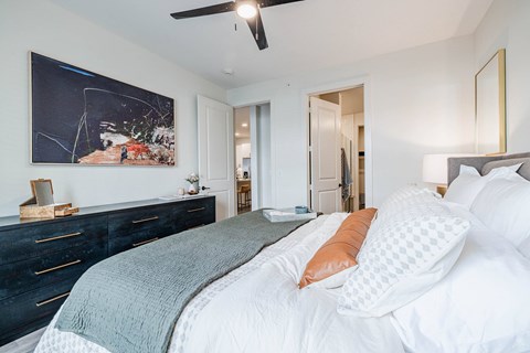 A bedroom with a large bed and a painting on the wall.